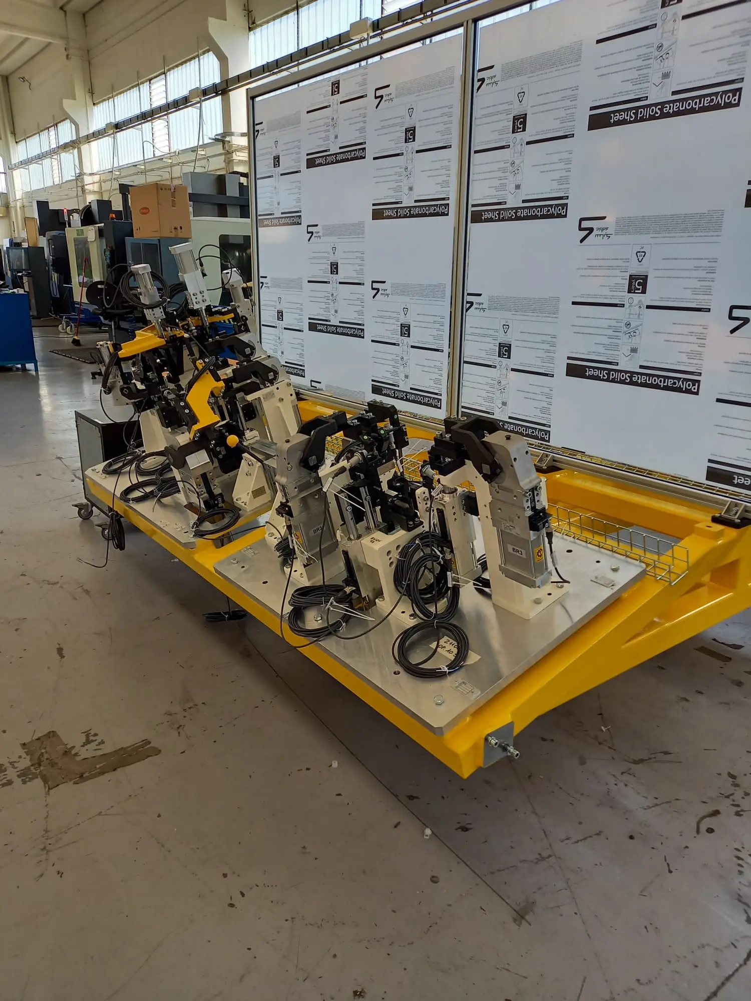 Clamping fixture on a yellow base frame, with pneumatic units and clamps, in the machine shop
