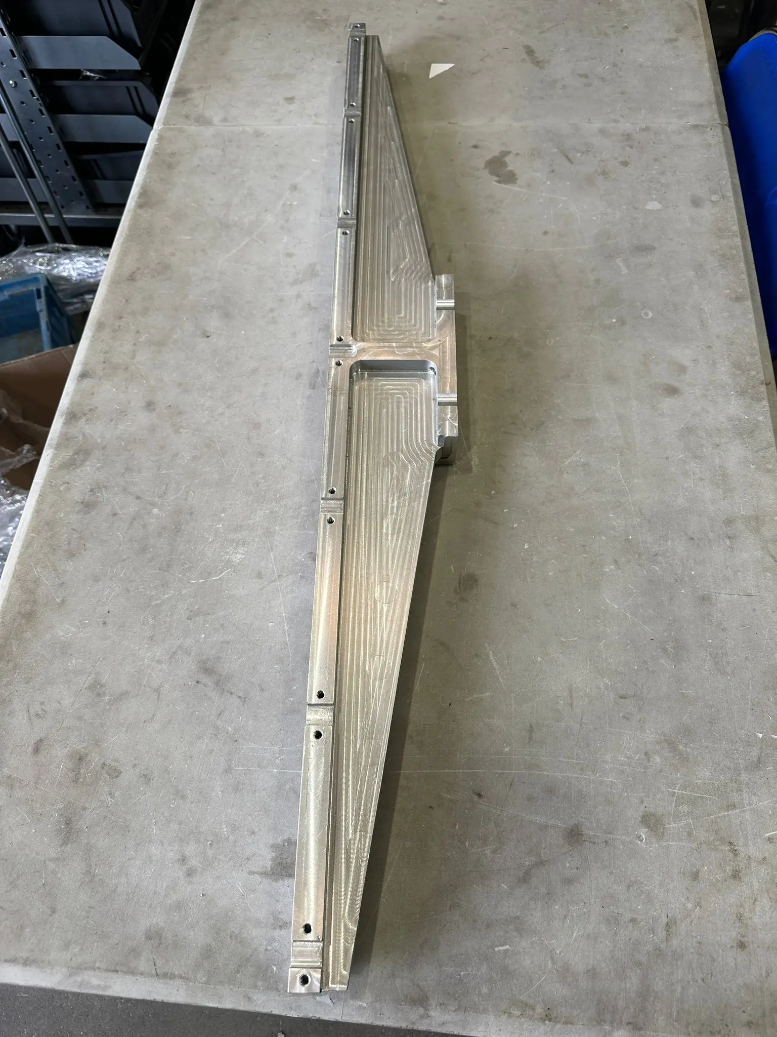 CNC-milled aluminium beam with the toolpath visible on the surface, resting on a surface plate